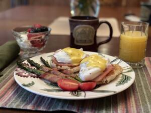 breakfast with poached eggs on ham and muffin with bacon-wrapped asparagus