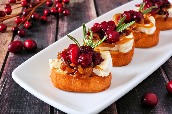 Crostini appetizers with cranberries, brie and caramelized onions